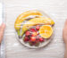 Manos Masculinas Envolviendo un plato de frutas con film alimenticio