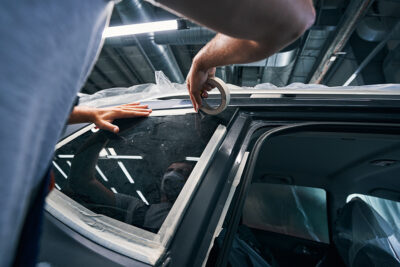Reparador aisla ventanas de auto con masking tape automotriz